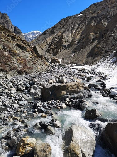 A cascading mountain stream winds through a rugged rocky valley