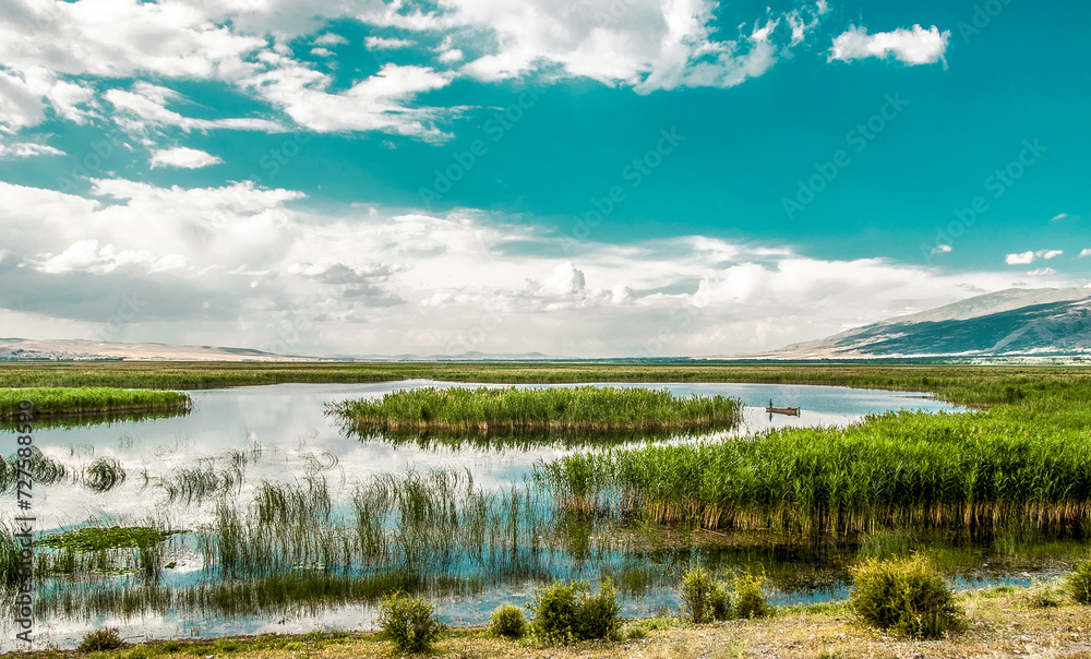 Fisherman is standing in the old, wooden rowboat and catching the fish on cloudy day. Karamik Lake Afyonkarahisar Turkey