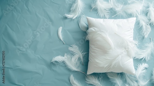 Soft white pillow amidst scattered feathers on blue backdrop photo