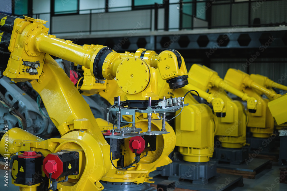 Row of yellow automatic welding robot arms at automobile industrial factory.