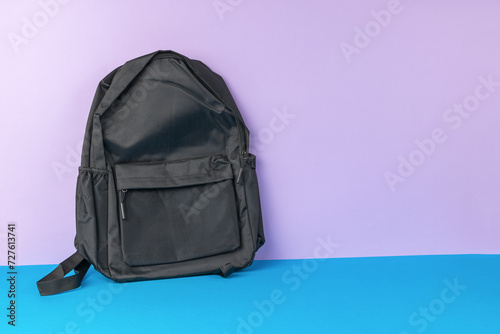 A black backpack on a two-tone background.