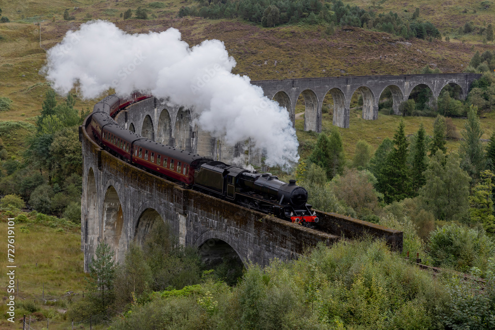 Naklejka premium Jacobite Great Western Railways Steam train crosses the Glenfinnan viaduct in the Scottish Highlands. Famous landmark in Scotland featured in Harry Potter
