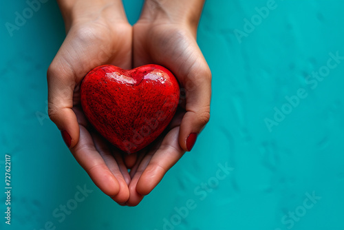 Hands holding a red heart on a blue background photo