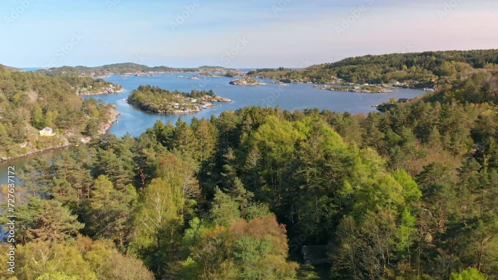 Dense green forest along the shoreline of a Norwegian archipelago. Cabins along the shoreline. Dense green forest along the shoreline of a Norwegian archipelago. Cabins along the shoreline.