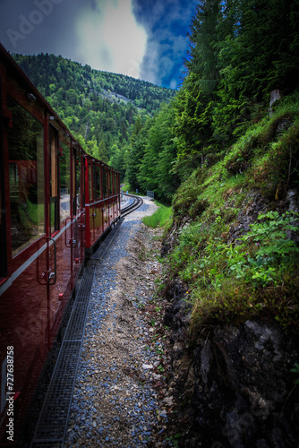 Red tourist train running lying across mountains with foggy background,Austria