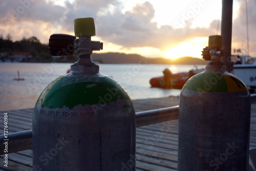 Close up picture of scubatanks with the ocean and boats in the backroud at sunset. Preparing for a nightdive. photo
