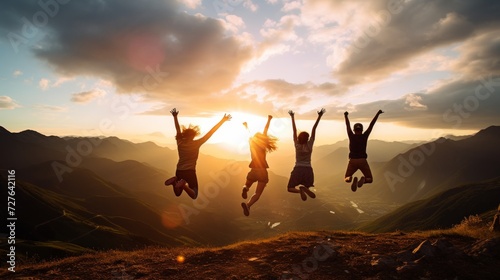 Silhouette of group of people joyfully jumping in front of majestic mountain at sunrise