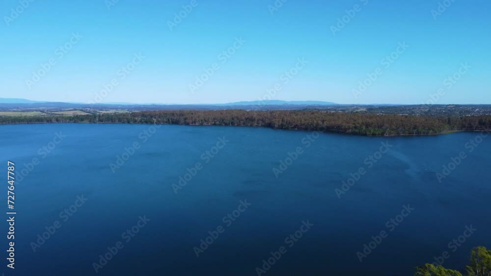 Aerial View of a Serene Lake Surrounded by Forests and Mountains Under a Clear Blue Sky Aerial View of a Serene Lake Surrounded by Forests and Mountains Under a Clear Blue Sky