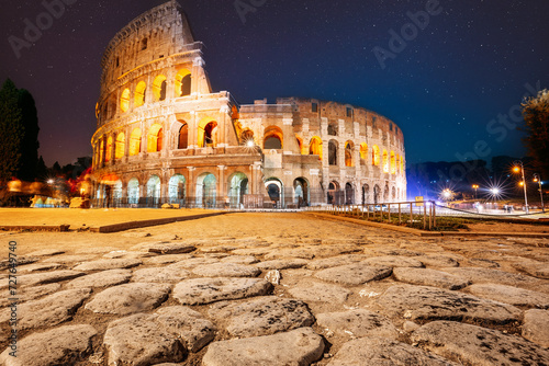 Rome, Italy. Colosseum Also Known As Flavian Amphitheatre In Night. Calmness Night Time. Bright Blue Night Starry Sky. Amazing Star Sky. Travel Italy Concept. Spirit Of Travel. Zeitgeist.