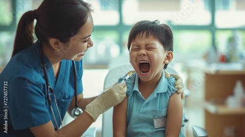 Asian nurse gives injection to crying child at hospital photo