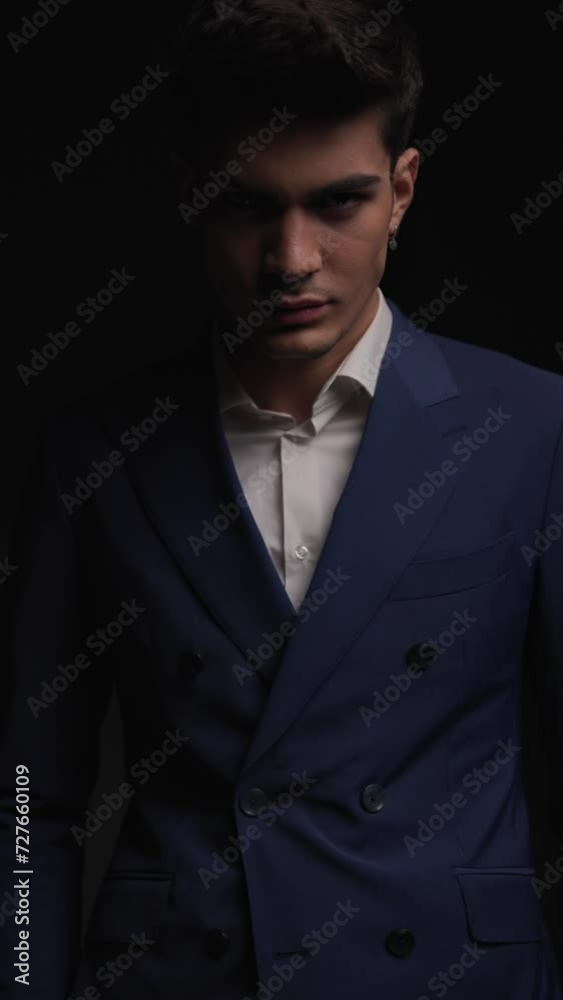 classy businessman in double breasted blue suit standing on black background with strobes effect and looking sexy classy businessman in double breasted blue suit standing on black background with strobes effect and looking sexy