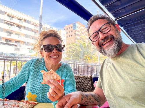 One adult couple taking selfie at the restaurant eating pizza margherita together with smile. People client enjoy pizzeria fresh tasty food together having picture with mobile phone at table