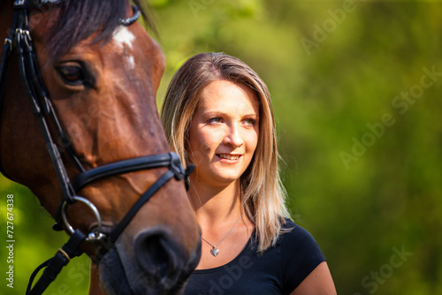 Young brunette woman in head portrait next to her horse. Sharp main subject.