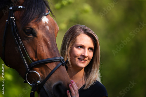 Young brunette woman in head portrait next to her horse. Sharp main subject.