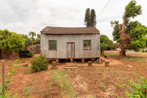 Weathered Corrugated Iron Shack in an African Suburb, Built During Colonial Times, Elevated on Stilt Foundations with Aging Earth Brick Pillars