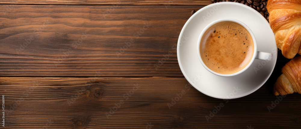 Croissants and a cup of coffee on a wooden table, flat lay. Horizontal banner. Copy space for text Croissants and a cup of coffee on a wooden table, flat lay. Horizontal banner. Copy space for text