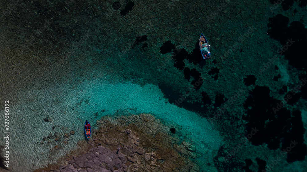 Obraz premium Aerial view of Cala Sapone, S. Antioco bay in Sardinia. Crystal clear sea, moored boat and white sand.