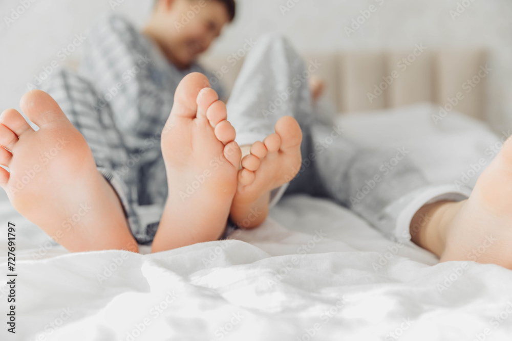 the bare, clean feet of two children, offspring, lying side by side under the same blanket on the bed. morning relaxation, cozy rest. cute pictures of baby feet the bare, clean feet of two children, offspring, lying side by side under the same blanket on the bed. morning relaxation, cozy rest. cute pictures of baby feet
