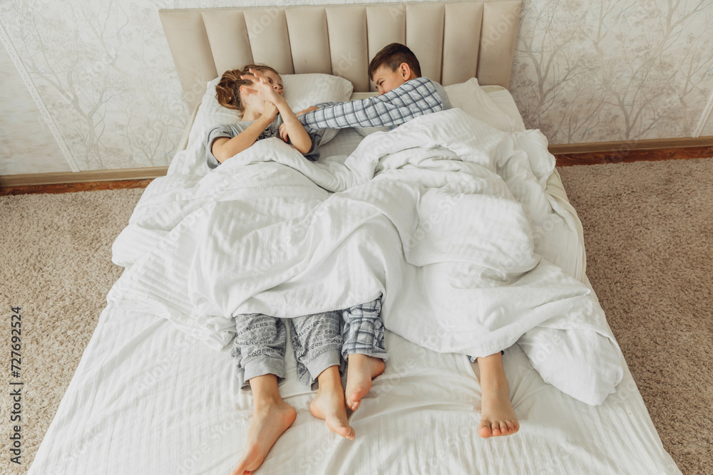 the bare, clean feet of two children, offspring, lying side by side under the same blanket on the bed. morning relaxation, cozy rest. cute pictures of baby feet the bare, clean feet of two children, offspring, lying side by side under the same blanket on the bed. morning relaxation, cozy rest. cute pictures of baby feet