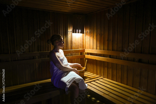 Young girl relaxing on wooden bench in sauna photo