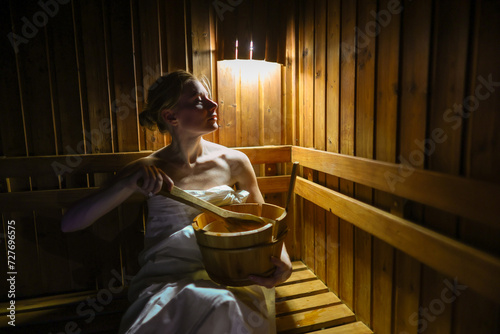 Young woman is taking a steam-bath at sauna photo