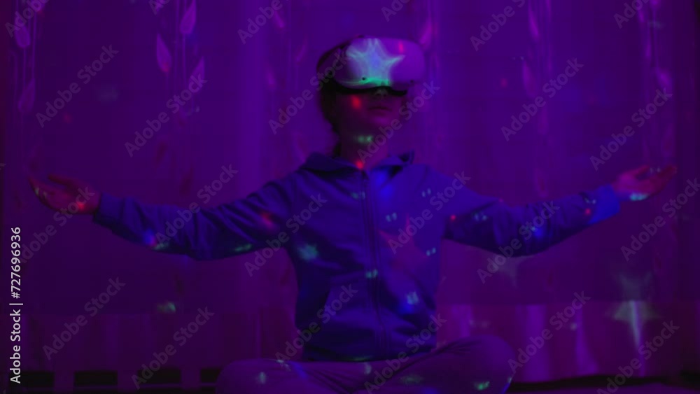 Girl of Virtual Reality Headset With Calming Meditation Exercise Yoga. Girl Using Virtual Reality Headset And Looking Around At Interactive Technology Colorful Illumination. VR Entertainment Immersive Girl of Virtual Reality Headset With Calming Meditation Exercise Yoga. Girl Using Virtual Reality Headset And Looking Around At Interactive Technology Colorful Illumination. VR Entertainment Immersive