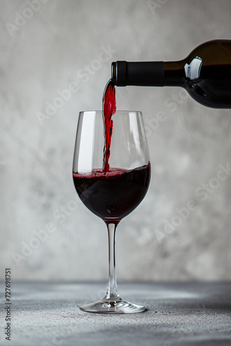 Red wine pouring into glass set. Smooth splash motion with pink background. Luxury and taste concept for design and print