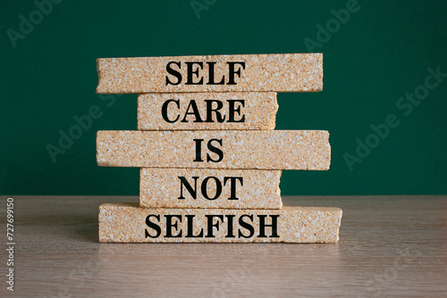 Self care is not selfish symbol. Concept words Self care is not selfish on brick blocks. Beautiful wooden table green background. Business do you know your limits concept. Copy space. photo