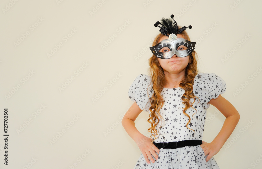 Child in a carnival masquerade mask. Festival, carnival, party. A little girl makes faces in a mask. Black and silver mask. Theater. Children's theater. Home theater. Performance for children. Child in a carnival masquerade mask. Festival, carnival, party. A little girl makes faces in a mask. Black and silver mask. Theater. Children's theater. Home theater. Performance for children.