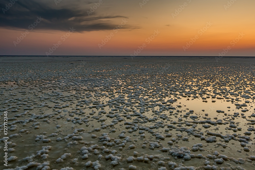 Sunset or sunrise on salt lake Elton (Russia) with mirror or reflection of low Cumulostratus or Stratocumulus clouds in the brine at golden hour. Evening or morning. Volrograd district. Sunset or sunrise on salt lake Elton (Russia) with mirror or reflection of low Cumulostratus or Stratocumulus clouds in the brine at golden hour. Evening or morning. Volrograd district.