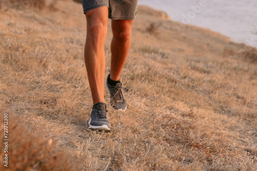 Legs of sporty man walking outdoor with warm sunset.