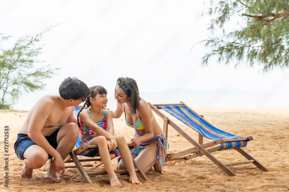 Happy Asian family enjoy and fun outdoor lifestyle travel ocean nature at tropical island beach on summer holiday vacation. Parents and little child daughter resting and playing together at the sea.