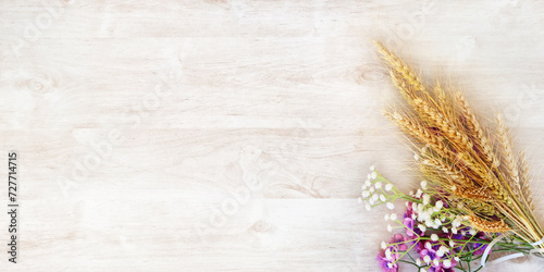 Ripe yellow wheat bouquet with purple and white flowers, on a white wooden surface. Intended for a greeting card for the holiday of Shavuot. with free space for text