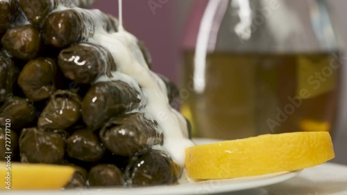 Adding Yoghurt Sauce on Turkish Traditional Food Yaprak Sarma. It Means Stuffed Grape Leaves. Also Known as Dolma. Ready to Eat. The Meal Filled with Rice and Mince. Slow Motion Close Up Shot.