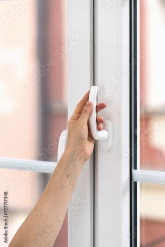 Selective focus on woman hand holding handle, turning up and opening pvc door or window at home.