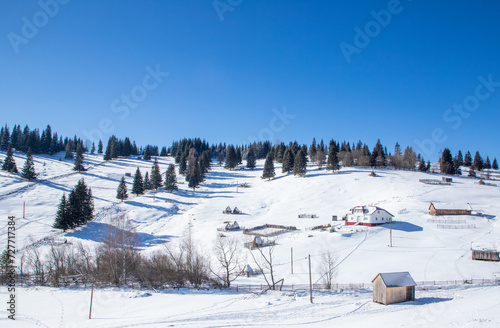Landscape with an isolated old house on the slope of a mountain in a rural area covered with snow - Romania. Beautiful countryside winter landscape
