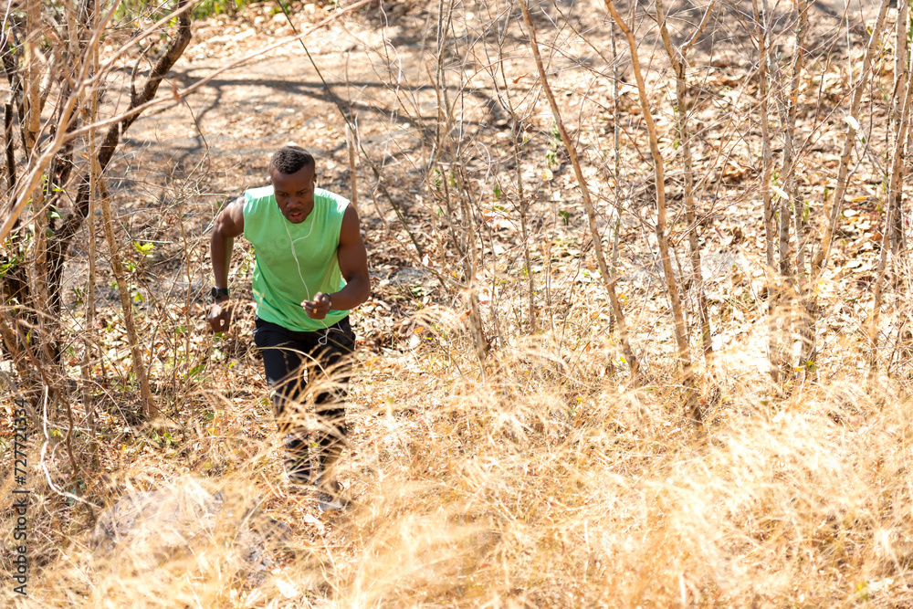 African man runner jogging and running trail in the meadow forest . Male guy running and exercising outdoors. Healthy and Sport Concept
