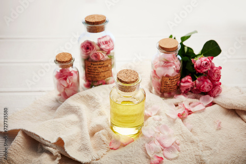 Composition with rose essential oil and flowers on white background