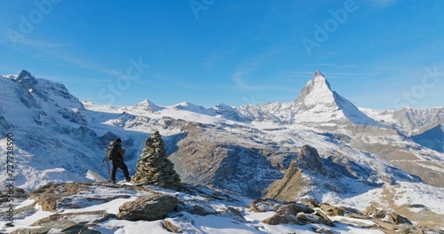 Panoramic landscape of Young man backpacker take a photo by camera at Switzerland mountain peak view point with iconic famous landscape Matterhorn background. Nature, Travel and Adventure concept.