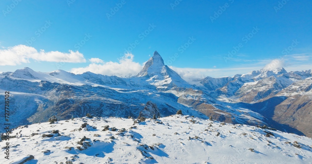 Majestic mountain peaks full of stacked rock hiker cairns with famous Matterhorn view background during winter in Switzerland. Swiss alps wonderful inspiring nature landscape.