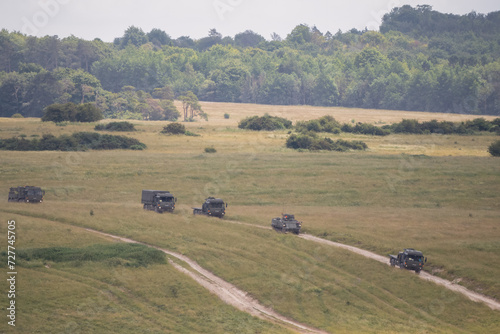 Tableau sur toile a convoy of camouflage military utility vehicles in motion through countryside