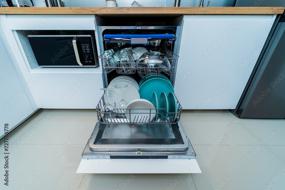 The white kitchen and opened dishwasher with clean dishes The white kitchen and opened dishwasher with clean dishes