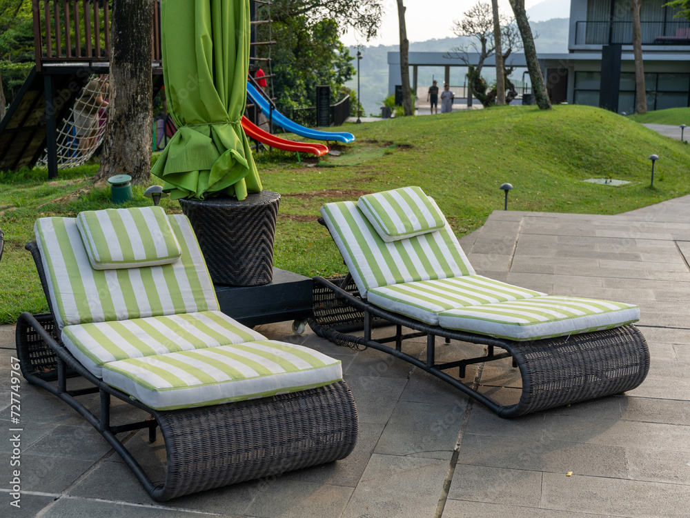Comfortable pair of outdoor chaises with green and white stripes on a stone floor