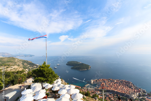  Dubrovnik - A majestic view of the cityscapes, seaside serenity, and mountain hills of Dubrovnik, with the Croatian flag proudly waving.