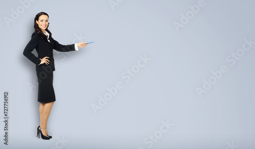 Full body length size view of happy excited smiling businesswoman showing pointing advertise copy space. Confident business woman wear black suit standing advertising, isolated on grey gray background