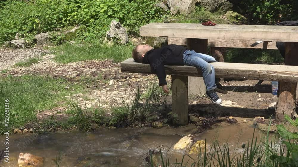 Little child lying down to rest on wooden bench in nature Little child lying down to rest on wooden bench in nature
