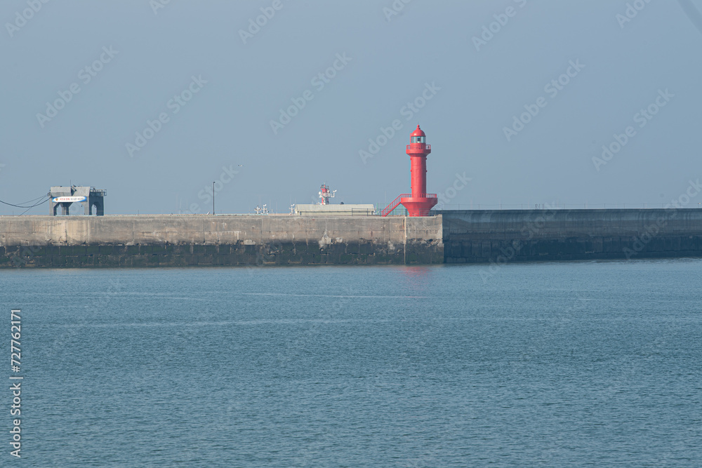 Scenery with blue sea and red lighthouse
