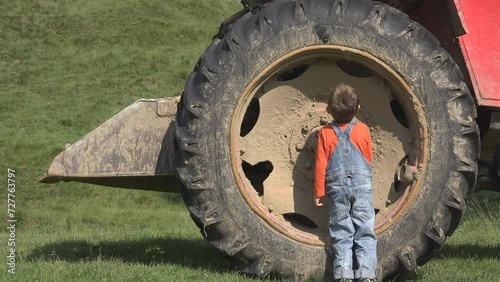 Small child inspecting the big tractor tire