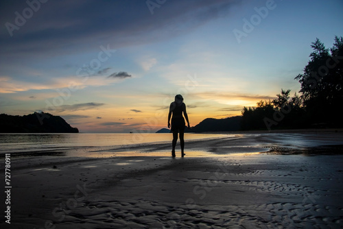 person walking on the beach at sunset