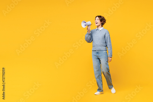 Full body young woman she wears grey knitted sweater shirt casual clothes hold in hand megaphone scream announces discounts sale Hurry up isolated on plain yellow background studio. Lifestyle concept.